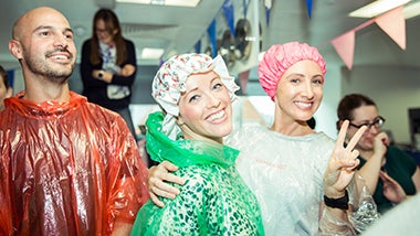 Smiling volunteers await their turn to be pied in the face for Cancer Research UK