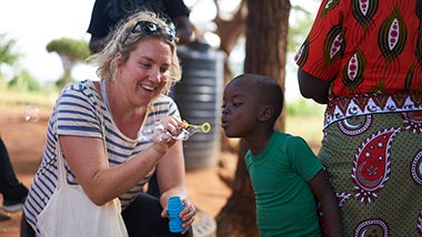 Isabel blowing bubbles with little boy in Tsavo