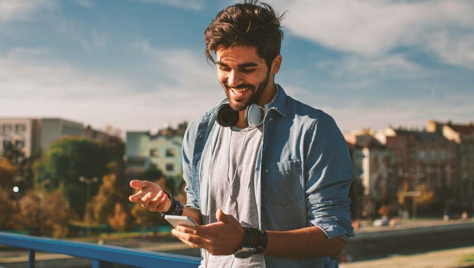 Young happy man using a smartphone  in the city